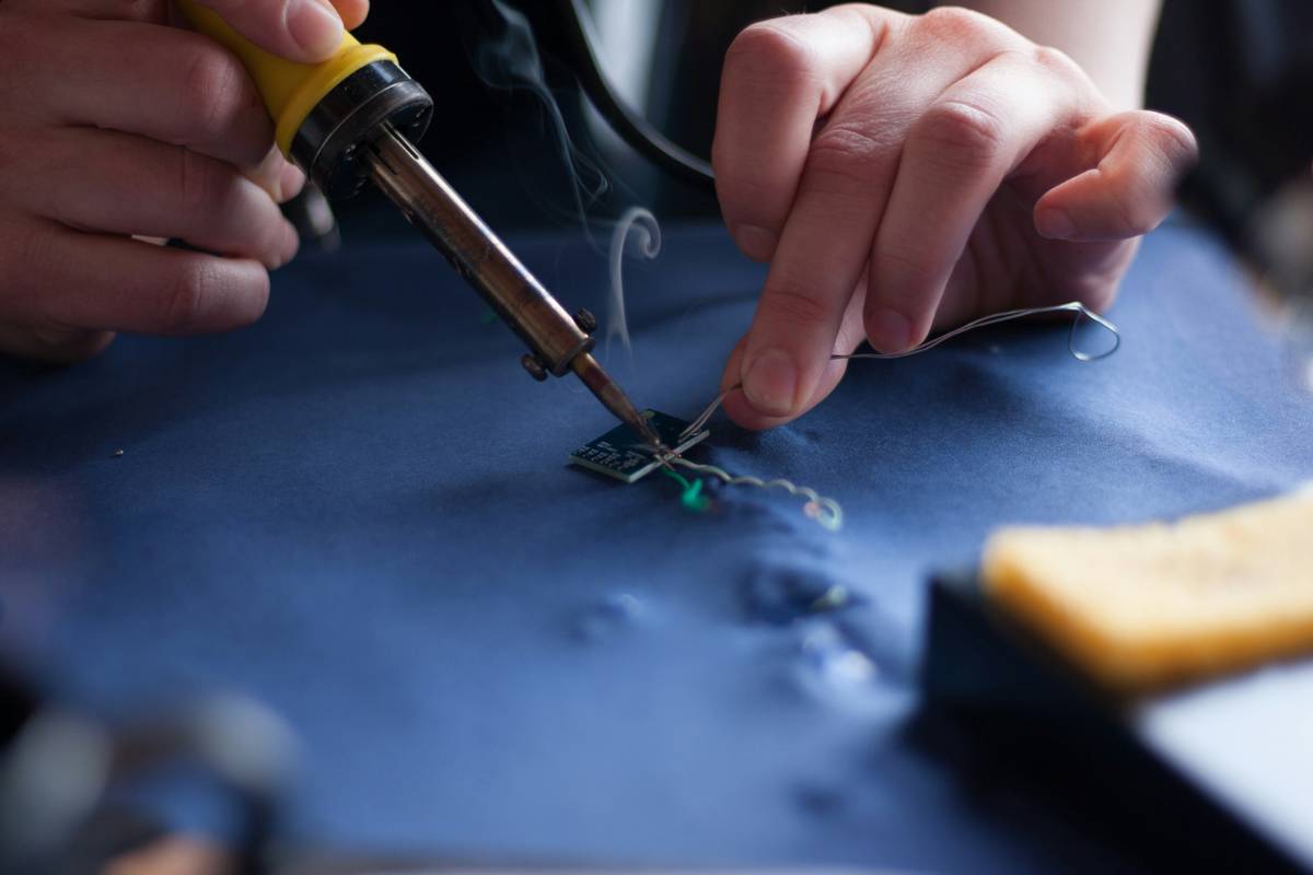 soldering tools solder iron in use on a circuit board with rosin-core solder and helping hands stand